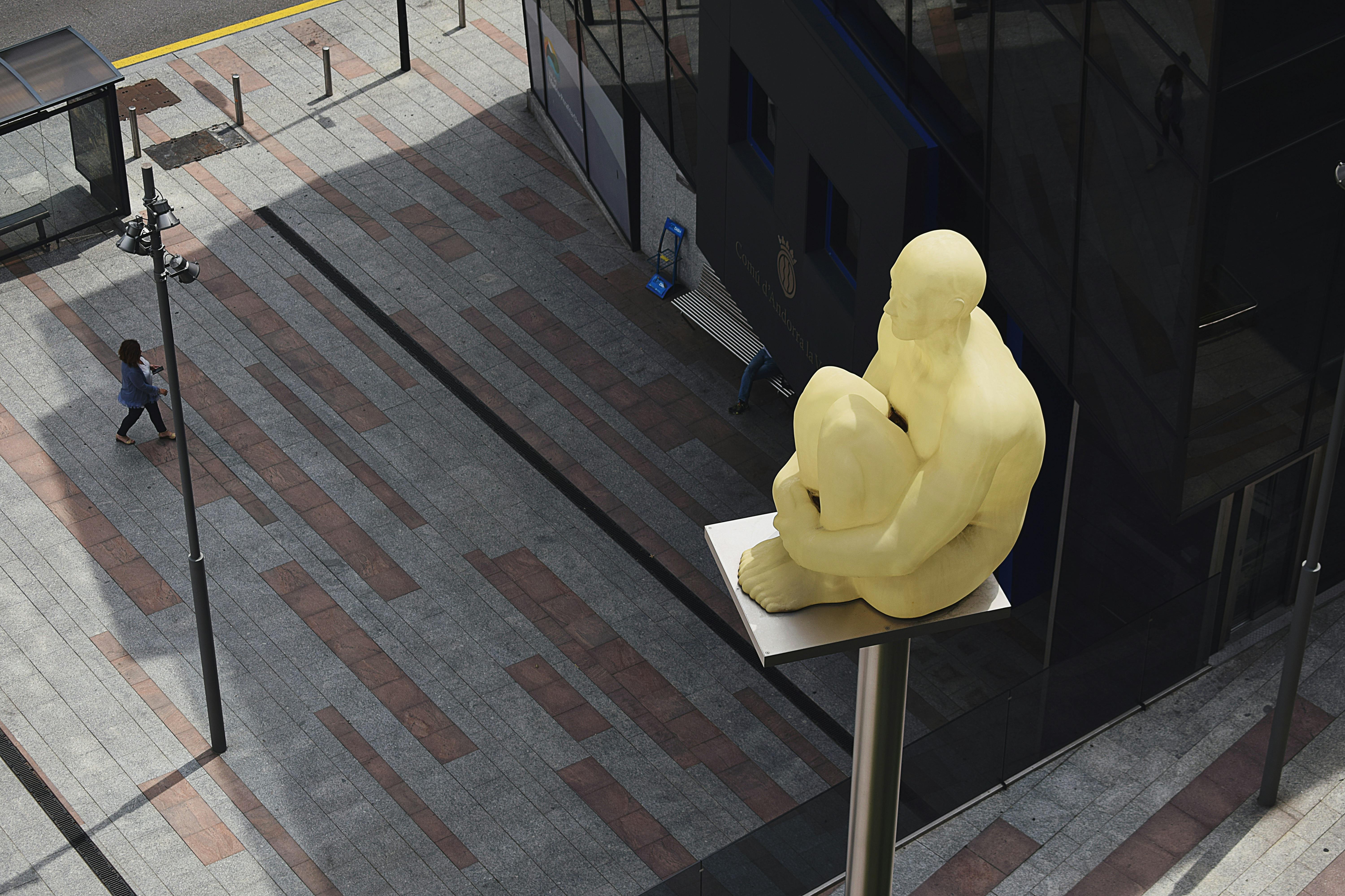 sitting man statue placed on gray metal post