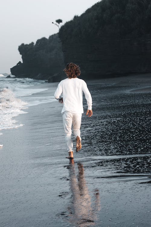 Free A Person Running Barefoot on Shore Stock Photo