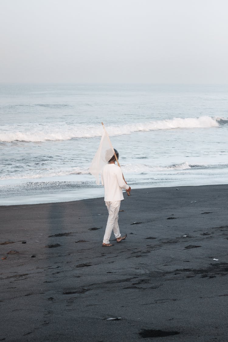 Woman In White Pullover And Pants Walking In Beach With Flag