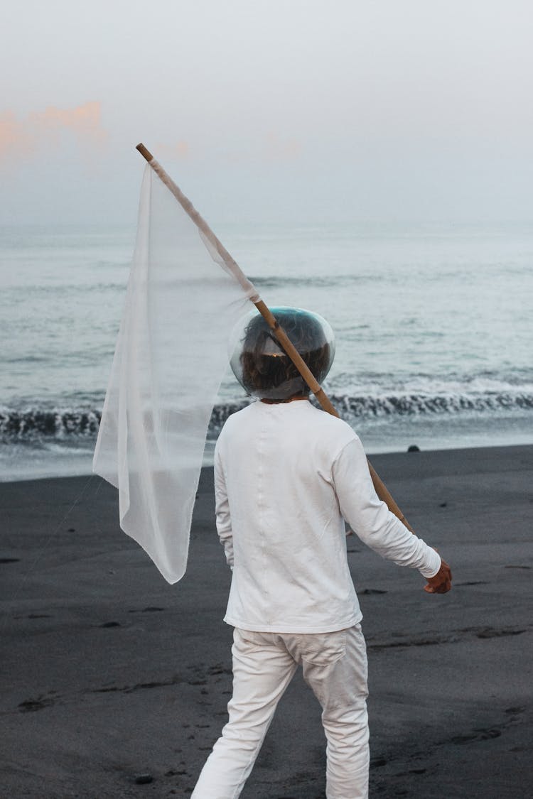 Person Carrying White Flag On Beach