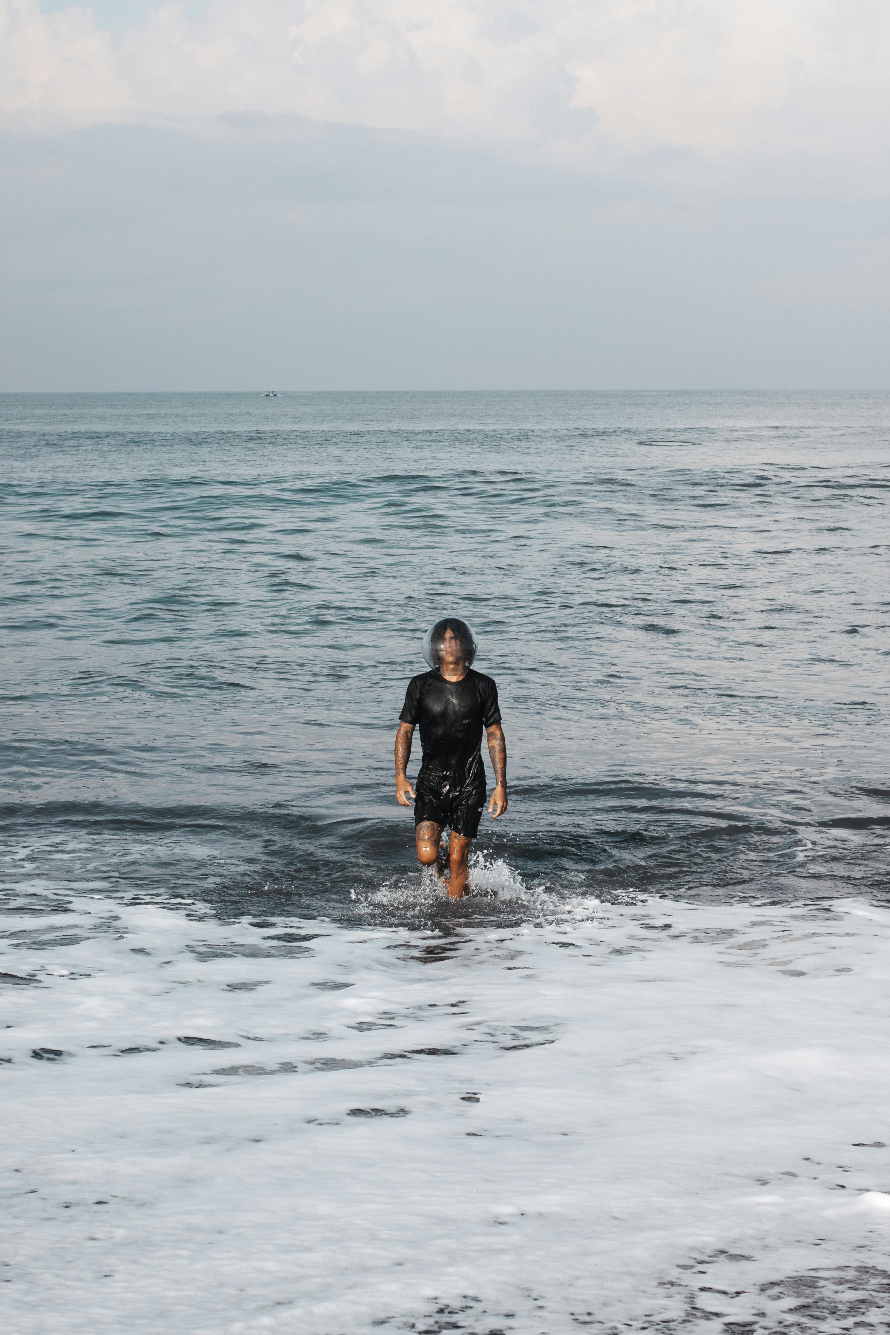 A Man with Fish Bowl on Head Walking on Water · Free Stock Photo