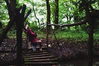 一名年轻女孩驾车穿过郁郁葱葱的森林中的一座乡村桥梁，捕捉着冒险与探索的氛围