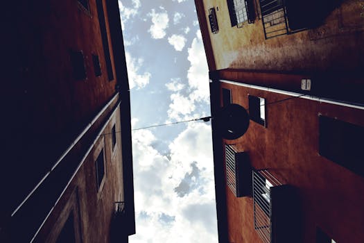 西班牙赫罗纳晴朗天空下，低角度拍摄的小巷建筑景观