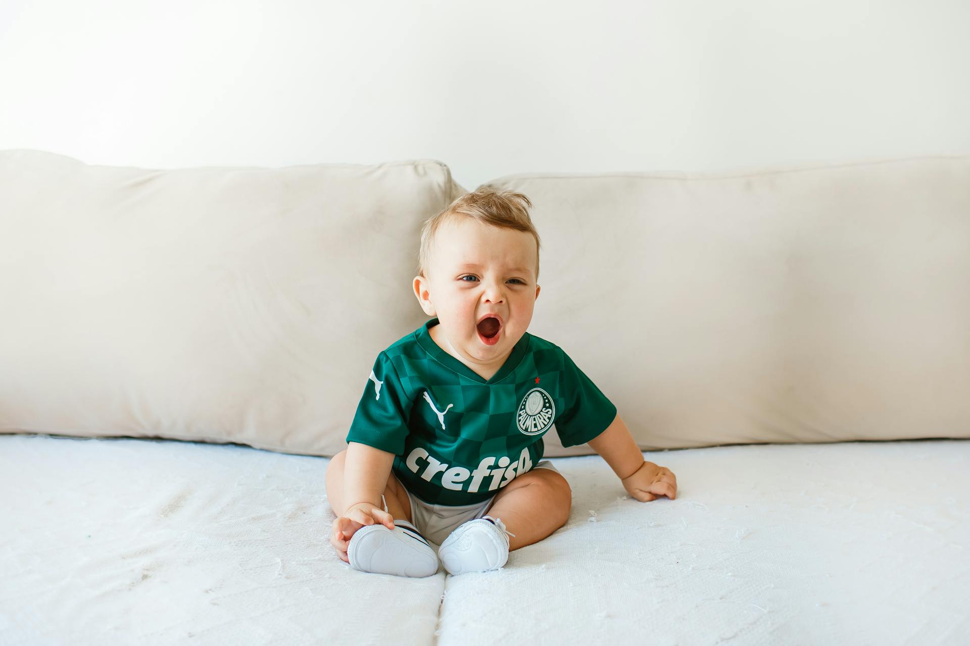 A Cute Baby Boy Yawning while Sitting on the Couch