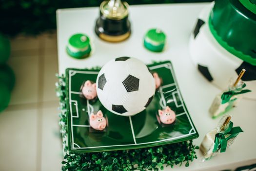 Playful soccer-themed birthday table setup with a football cake centerpiece.