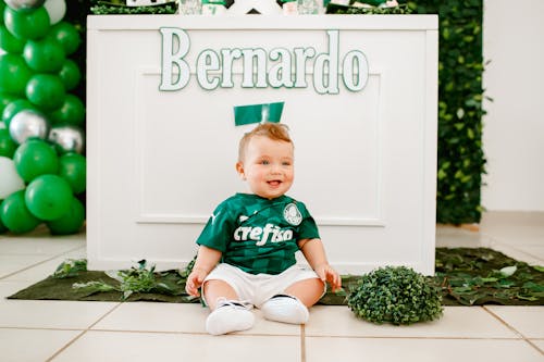 A Cute Baby Boy in Green Shirt while Sitting on the Floor