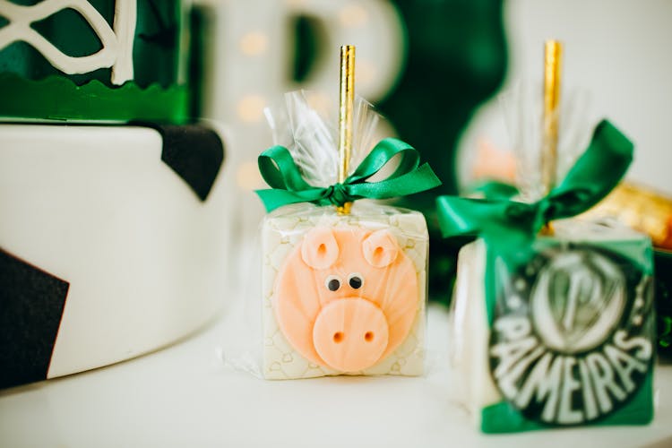 A White Cube Toy With Pig Face Wrapped With Plastic And Green Ribbon