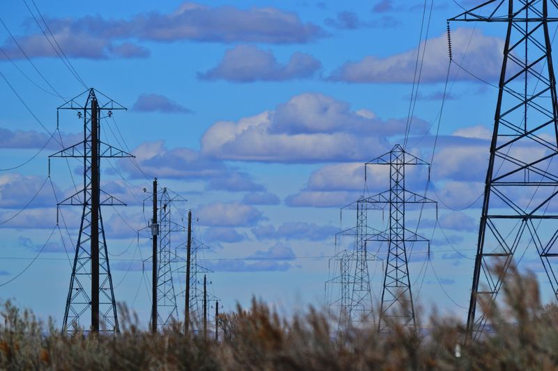 Transmission towers and power lines against a bright blue sky