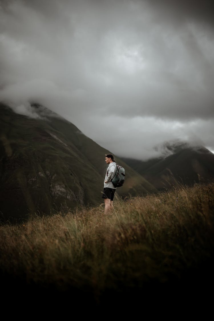 A Man In Black Shorts Standing On The Field While Carrying His Backpack