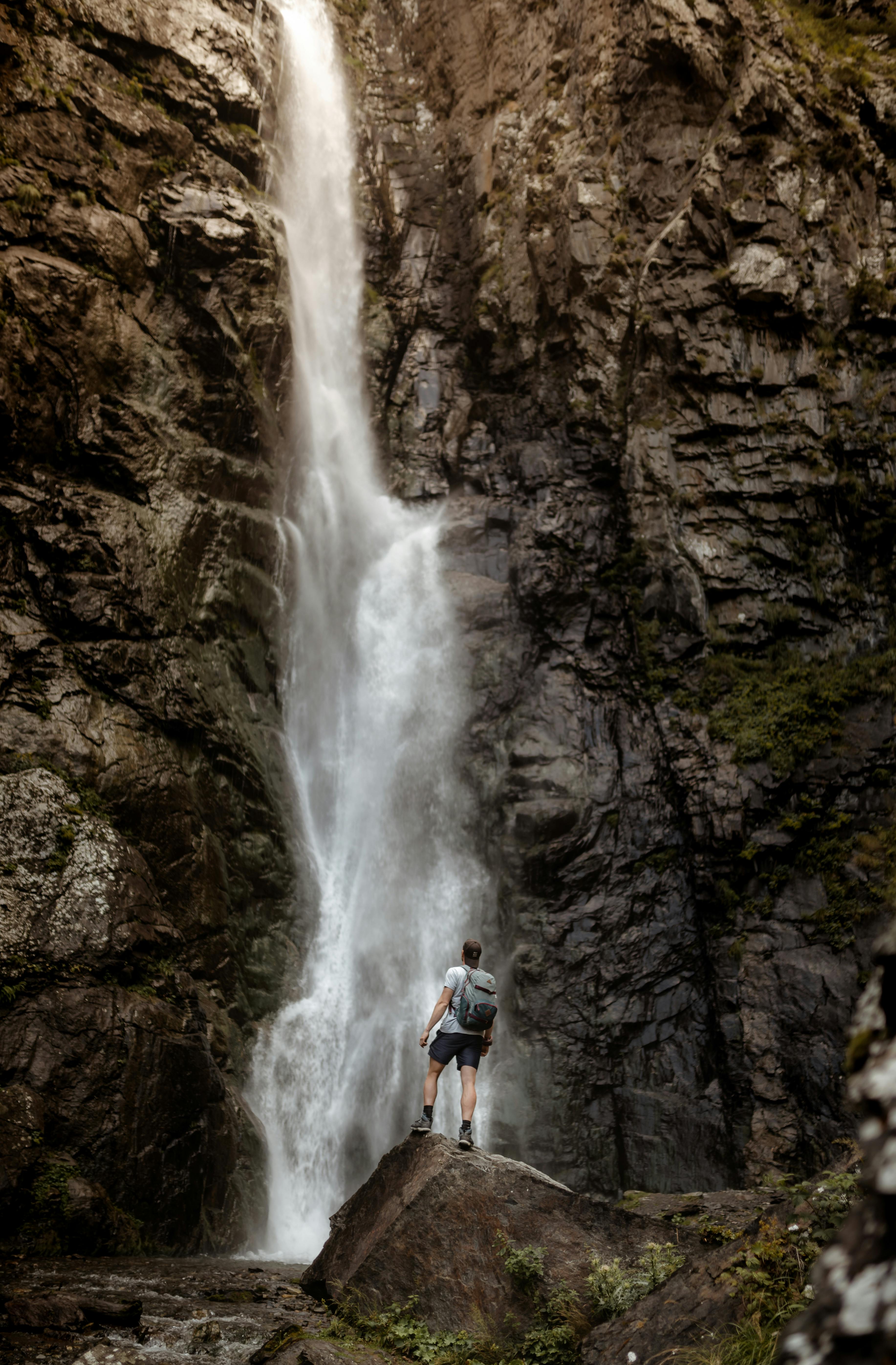 a man standing on rock in front of waterfalls