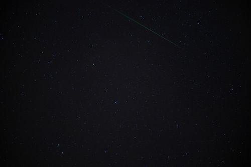 Free Capture of a starry night sky featuring a shooting star, perfect for astronomy enthusiasts. Stock Photo