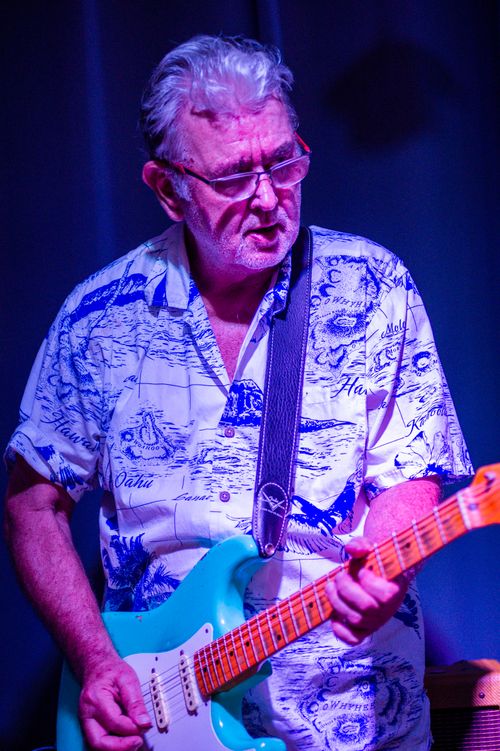 Free Elderly man playing electric guitar under a spotlight on stage. Stock Photo