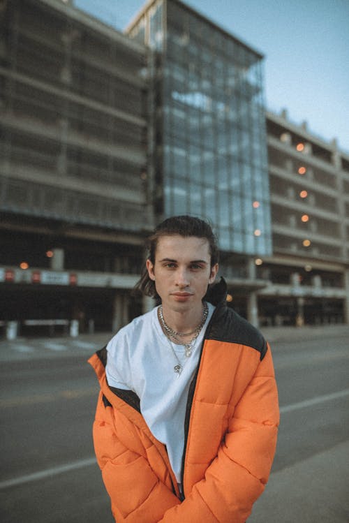 A Man in Orange Puffer Jacket Wearing a Silver Necklace