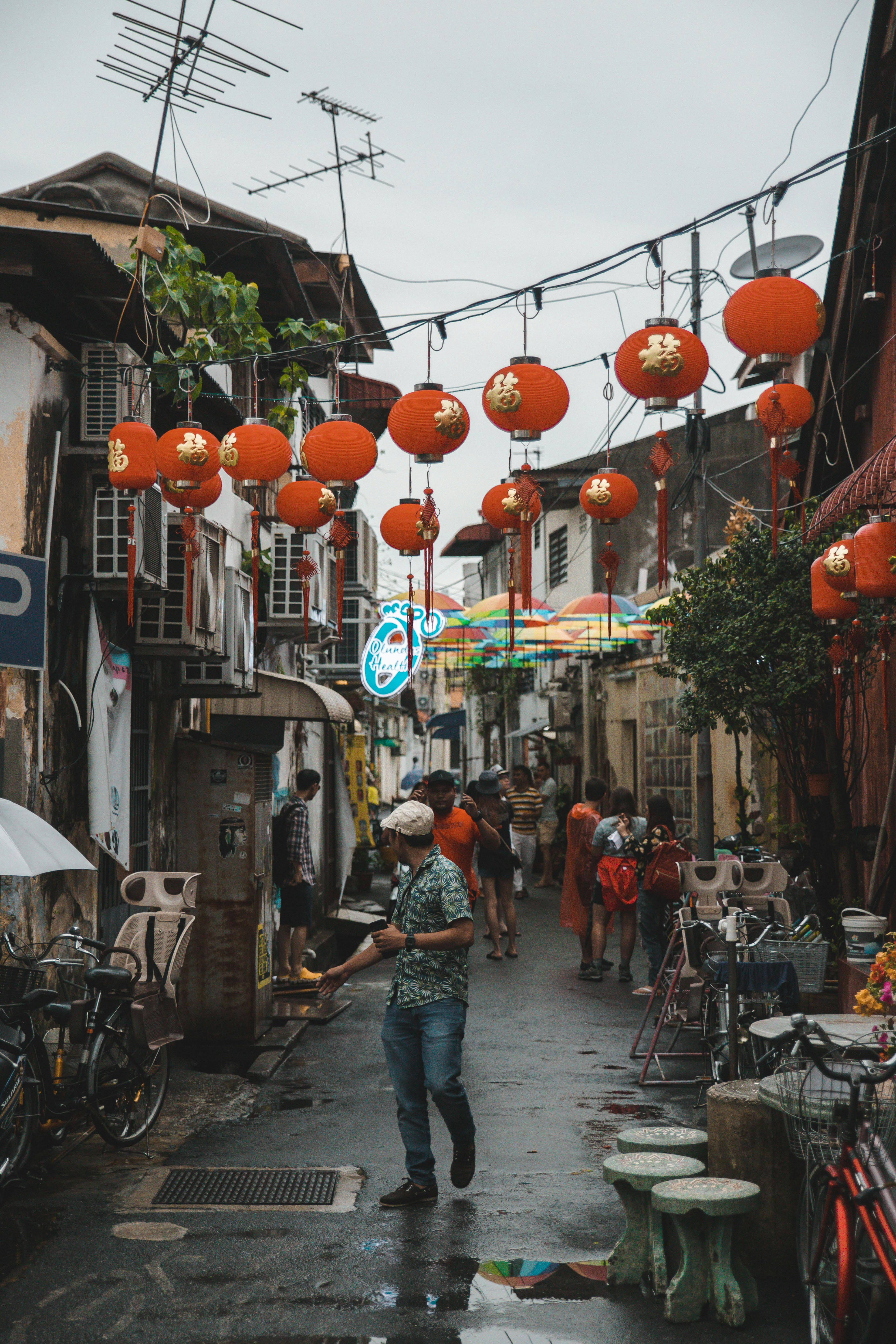 Vibrant alleyway with red Chinese lanterns and people walking, adding cultural charm.