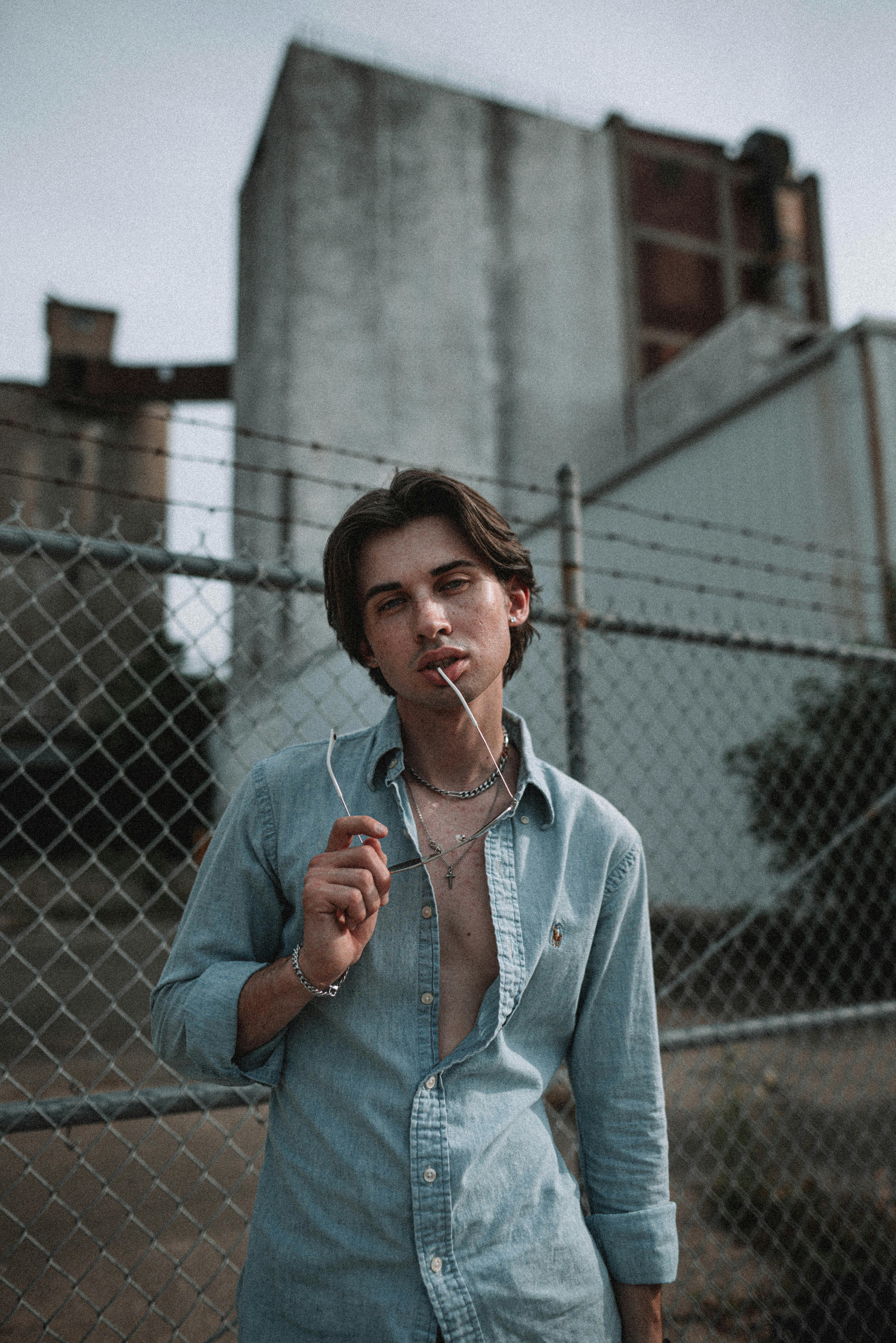 a young man in long sleeve shirt standing beside chain link fence