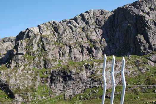A rocky mountain landscape with visible power lines under a clear blue sky, capturing rugged nature.