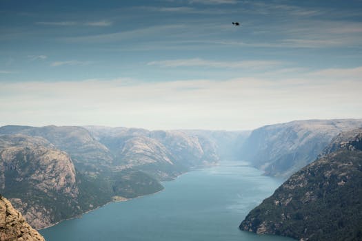 Breathtaking aerial view of a fjord surrounded by rocky mountains and clear blue skies.