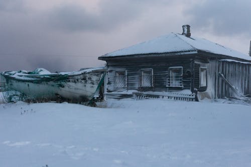 Abandoned Wooden House and Boat in Snow