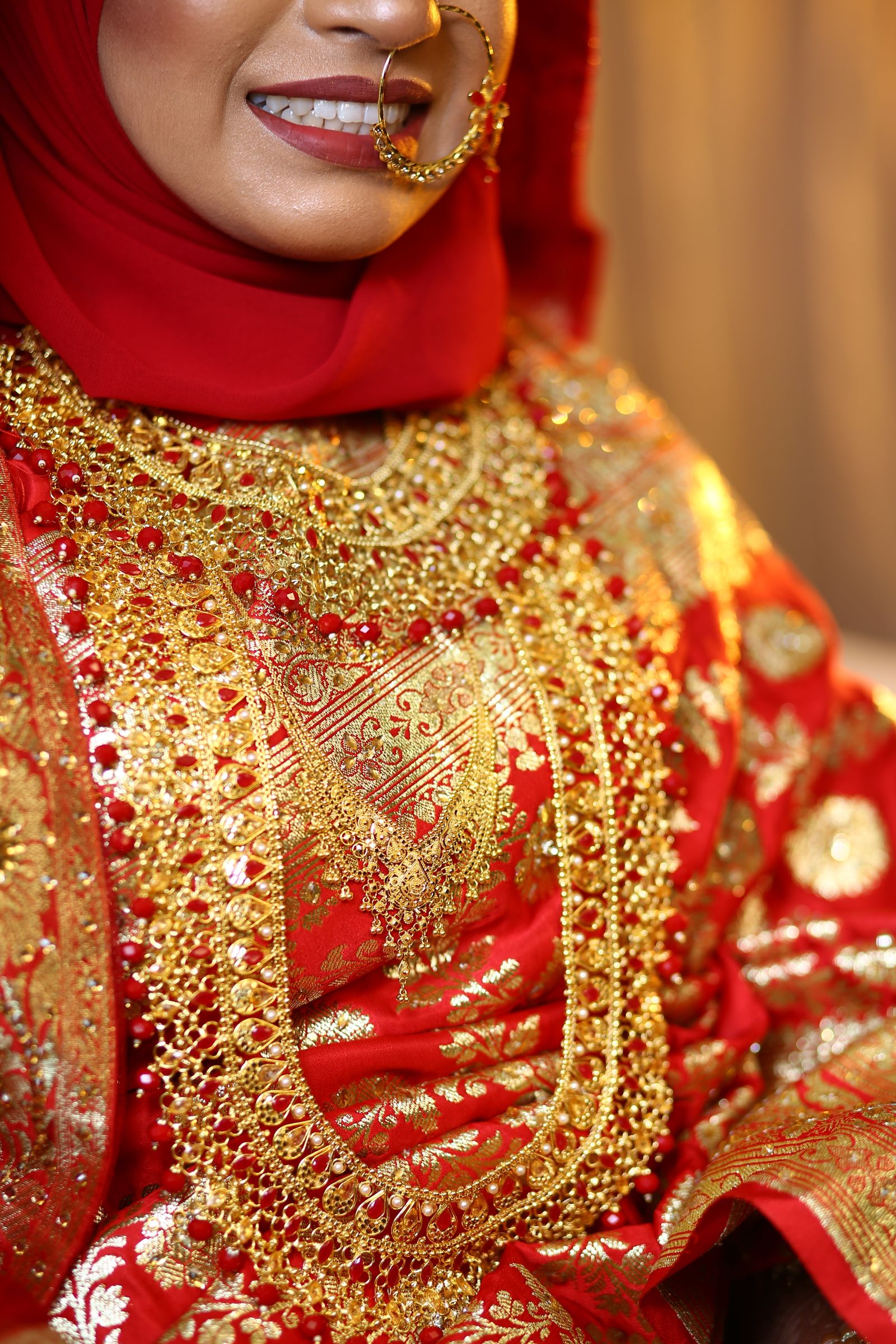 A bride in red and gold wearing a heavy traditional gold bridal set