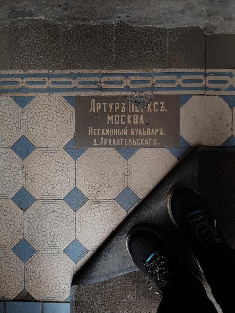 Person Legs Near Old Text On Tile In House