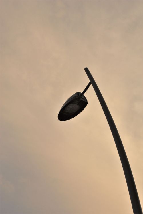 Free A modern street lamp silhouetted against a vivid sunset sky with orange hues, creating a captivating urban scene. Stock Photo
