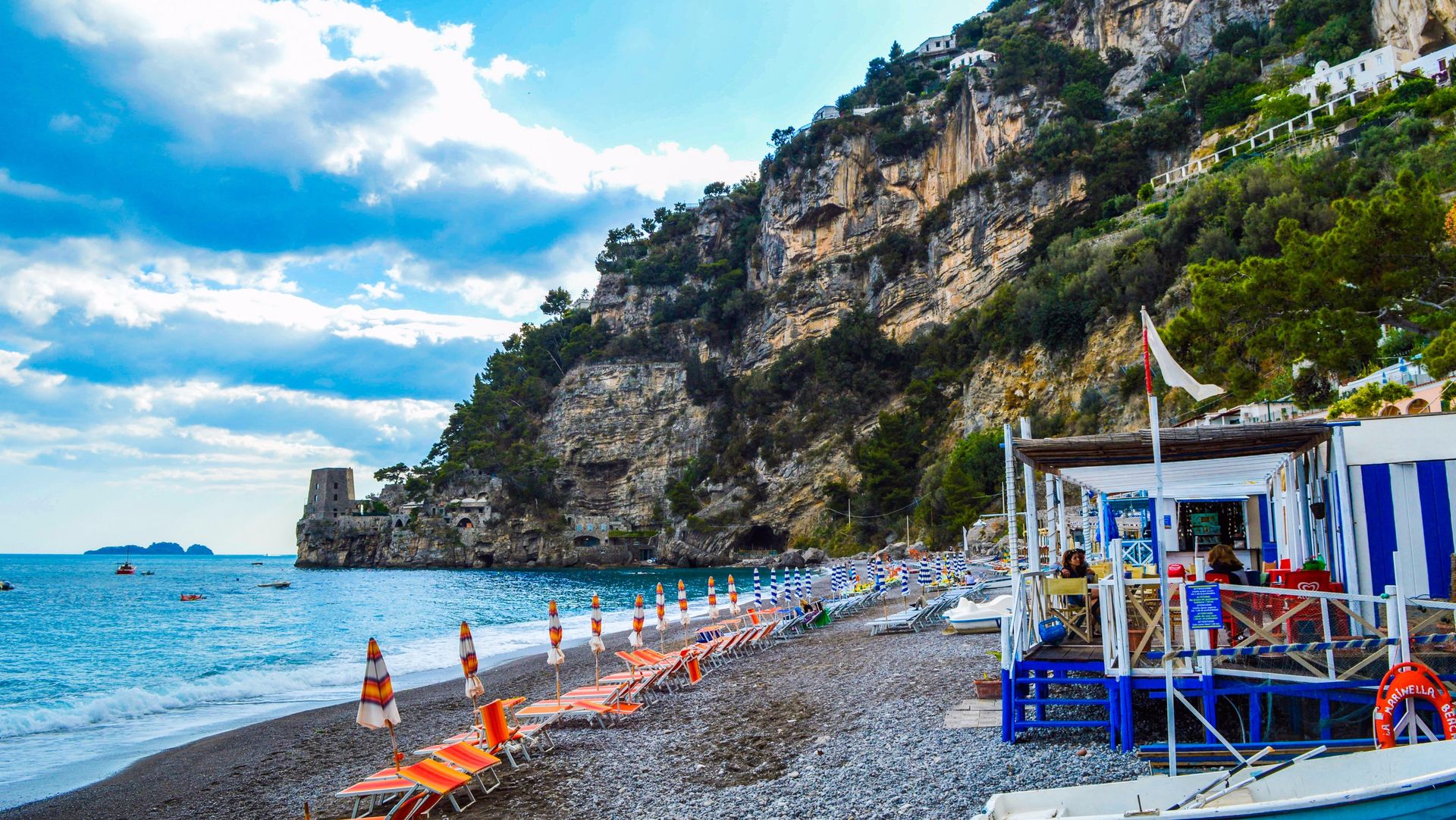 Vibrant Amalfi Coast beach with umbrellas and cliffs in Italy, perfect for travel and summer vacations.