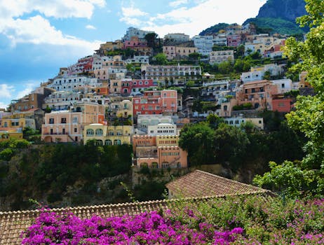 Vibrant houses built along the cliffside in Positano, Italy, surrounded by lush greenery and flowers.