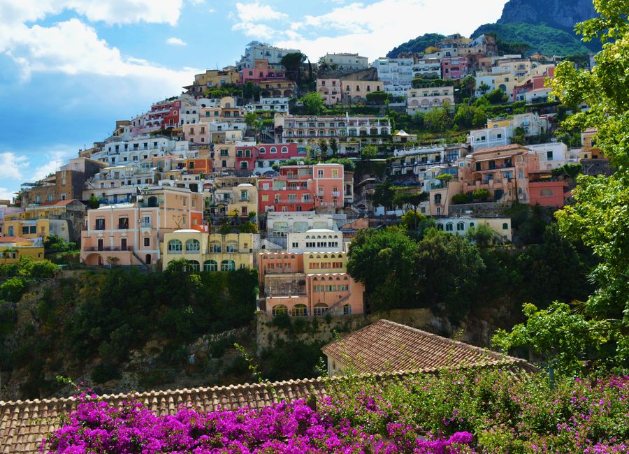 Vibrant houses built along the cliffside in Positano, Italy, surrounded by lush greenery and flowers.