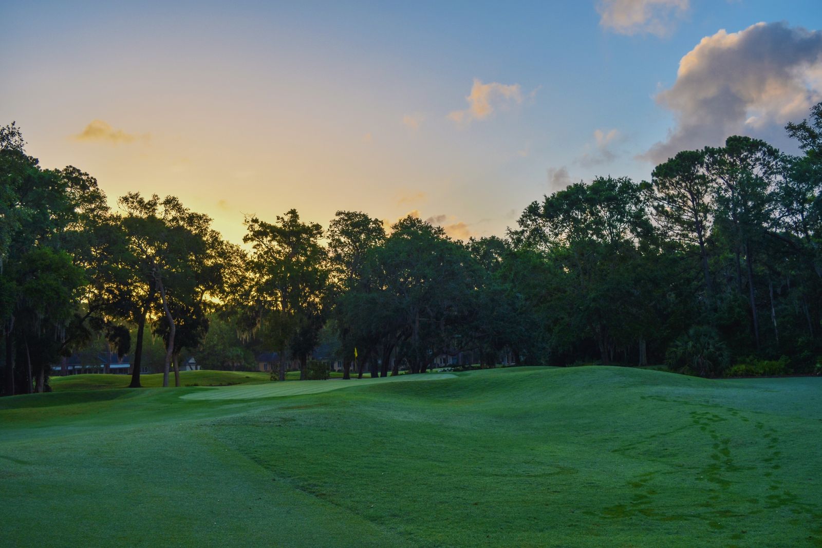 Golf course fairway and green under a colorful sunset sky