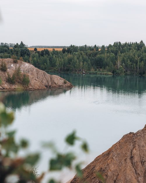 Free A tranquil view of a lake bordered by rocky formations and lush green trees, perfect for nature enthusiasts. Stock Photo