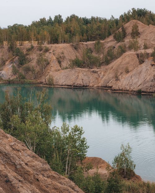 Free Beautiful river landscape with rugged hills and lush green trees on a calm day. Stock Photo