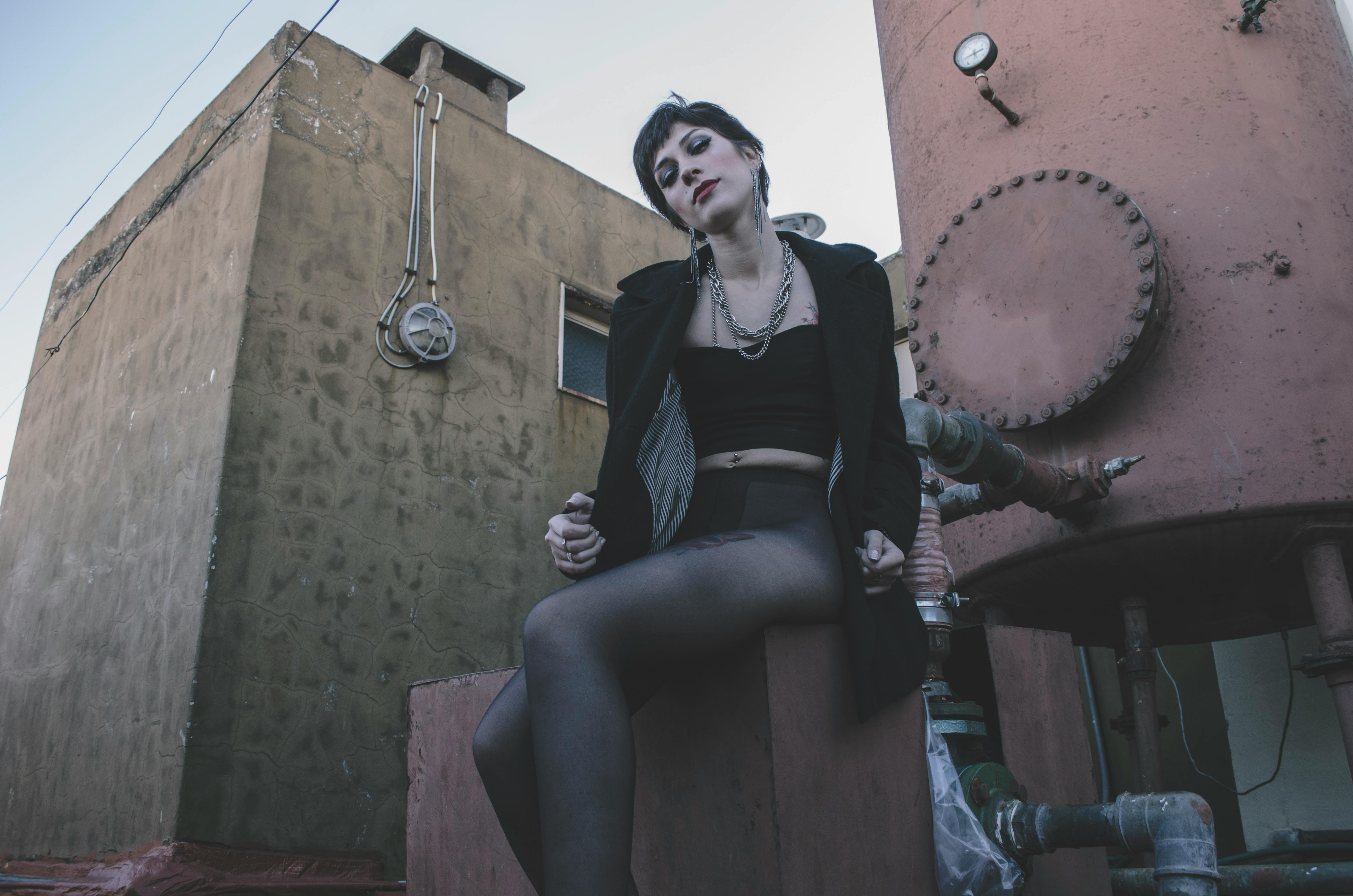 一位女性在工业城市环境中摆出前卫时尚的姿势，展现了现代风格