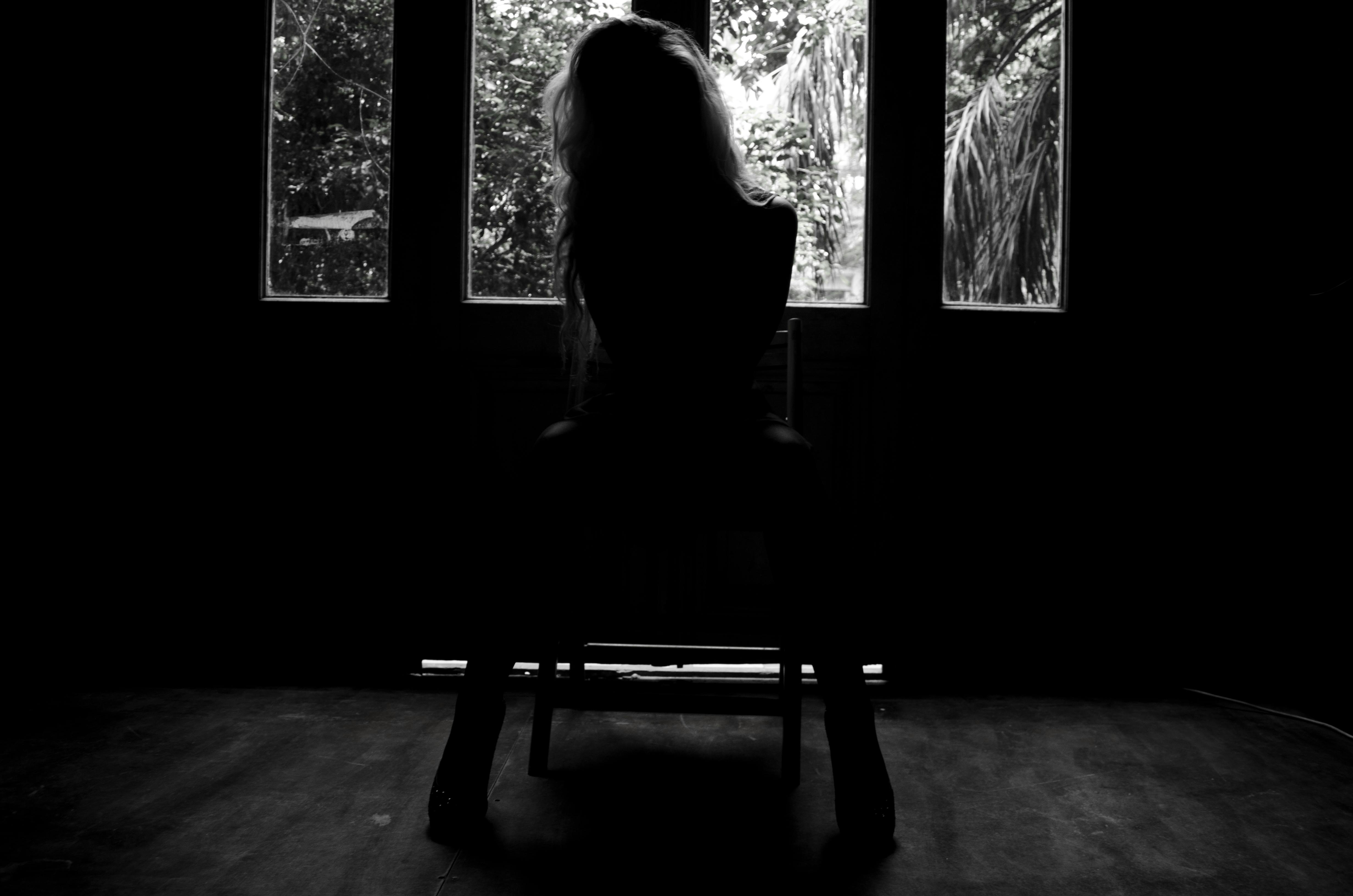 一名女子坐在室内，形成戏剧性的黑白剪影，窗外是景色