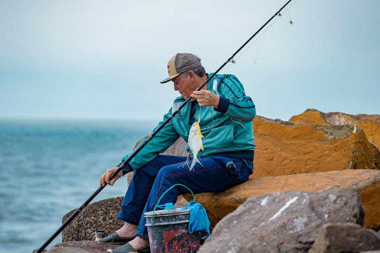 Elderly Man In A Blue Jacket Holding A Fishing Rod