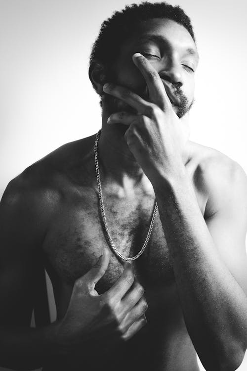 Grayscale Photo of a Man Posing with His Hand on His Mouth