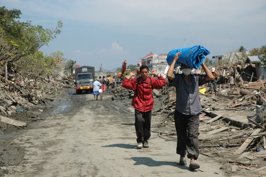 People walking through debris in Banda Aceh after a natural disaster, reflecting resilience.