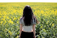 一位妇女站在广阔的黄色油菜花田里，享受着宁静的乡村风景