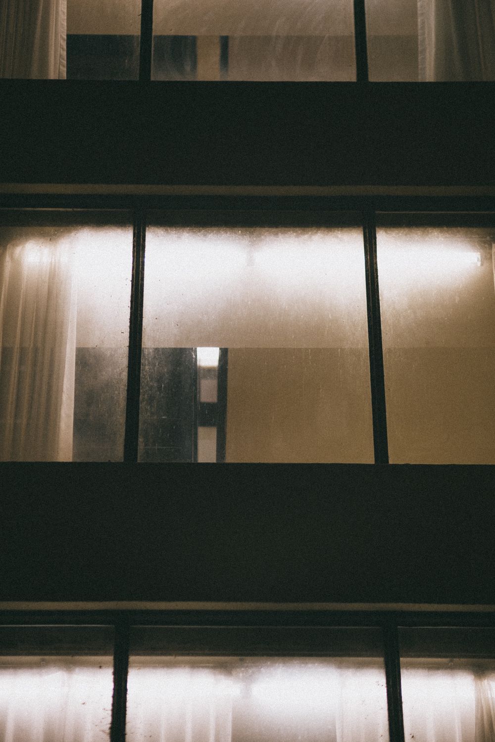 Rows of quietly lit windows on a building facade at night
