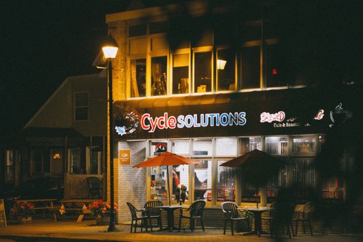 Nighttime view of Cycle Solutions café, a cozy spot for relaxation with warm lighting and outdoor seating.