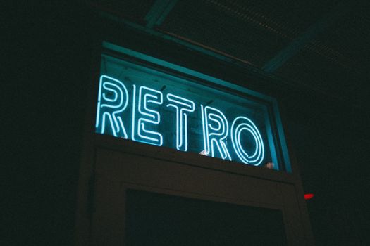 A neon-lit 'Retro' sign glowing in a dark urban environment, evoking nostalgia.