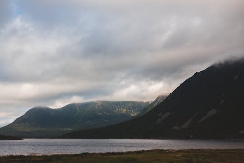 Immagine gratuita di catena montuosa, cielo coperto, lago