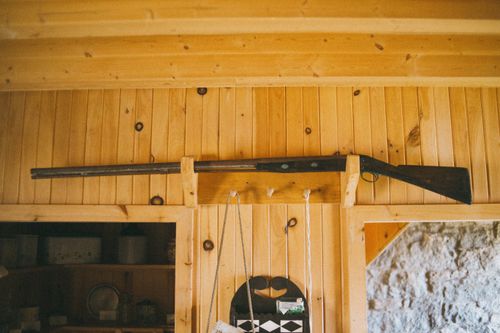 Free A rustic wooden cabin interior featuring a vintage hunting rifle mounted on the wall. Stock Photo