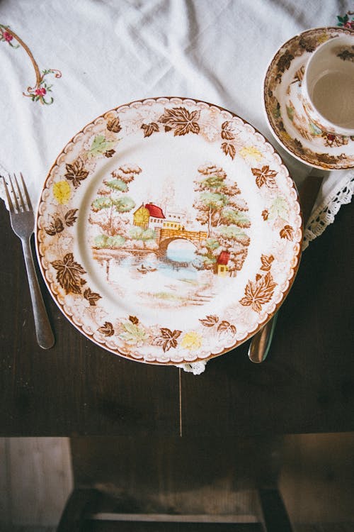 A Decorative Plate Beside Fork on Wooden Table