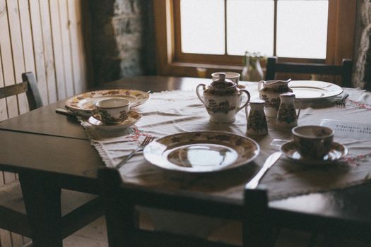 Charming rustic table setting with vintage crockery in cozy wooden room.