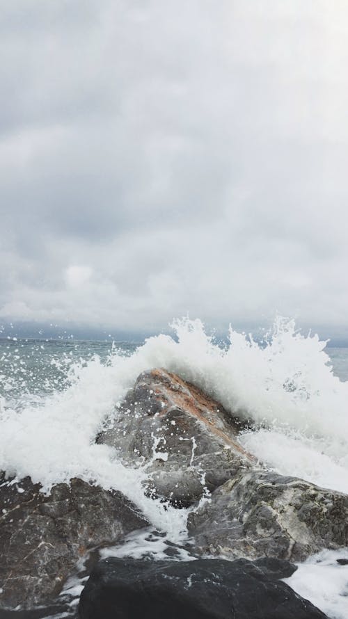 Человек, фотографирующий морские волны и серый бетонный камень