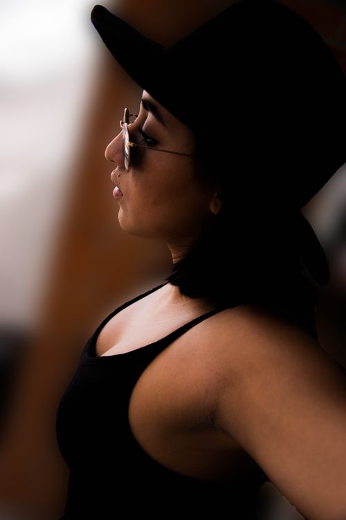 Free Side profile portrait of a stylish woman wearing a black hat and sunglasses, exuding confidence and elegance. Stock Photo