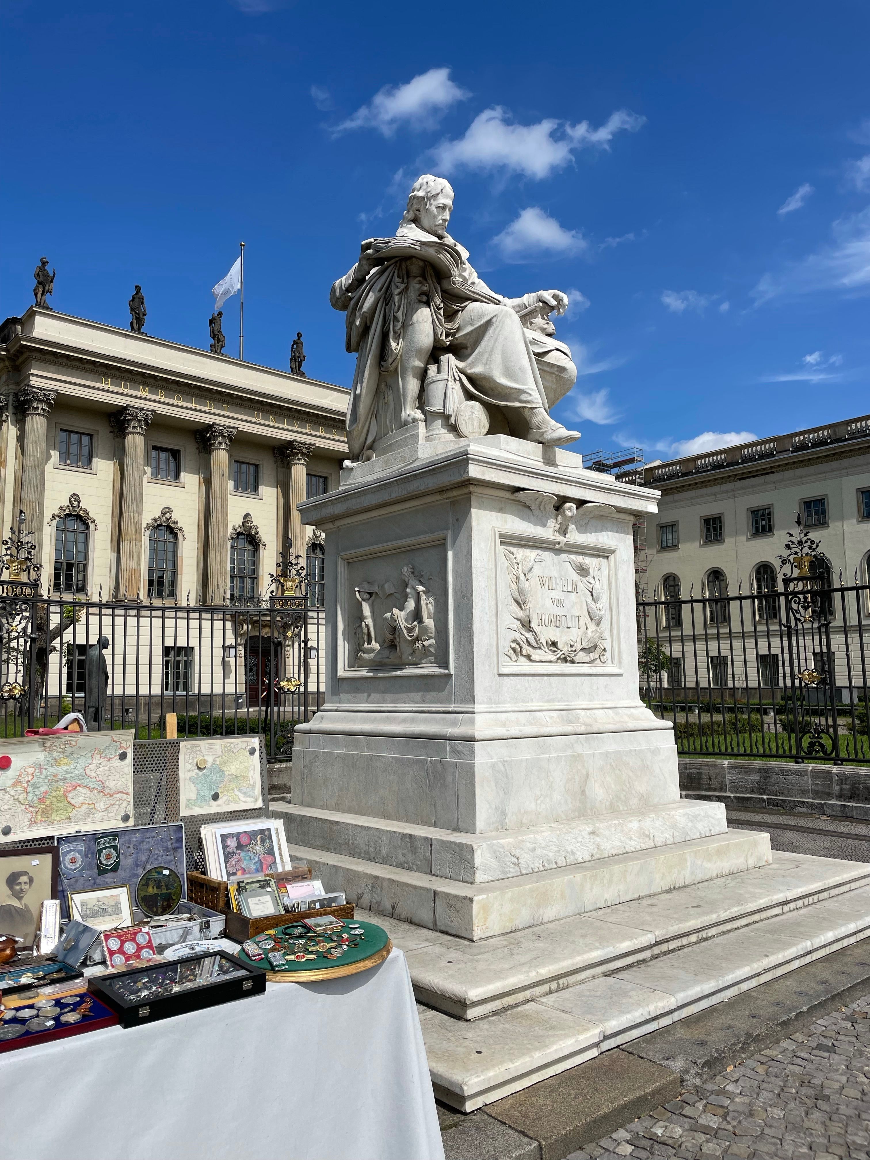 Statue of Wilhelm von Humboldt outside Humboldt University in Berlin under a clear blue sky.