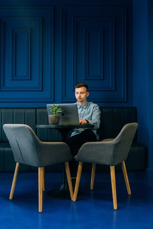 Photo of Man Using Laptop Sitting on Green Sofa