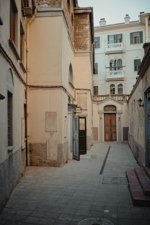 Free Explore a serene narrow alley with historic buildings, doors, and windows showcasing vintage architecture. Stock Photo
