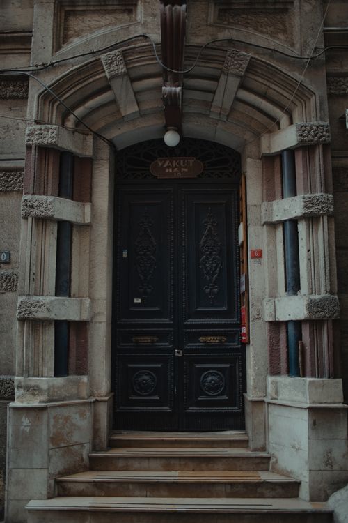 Free A beautifully carved black wooden door set in a classic stone arch façade. Stock Photo